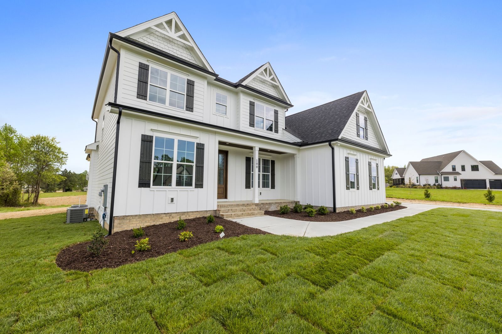 Two-story suburban home with black shutters, a covered porch, and a wide green lawn